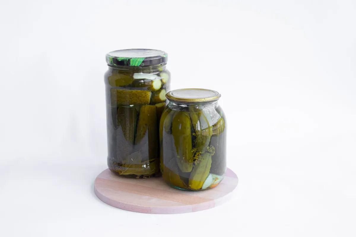 Mehrere Gläser mit buntem, fertig fermentiertem Gemüse stehen auf einem Holztisch.