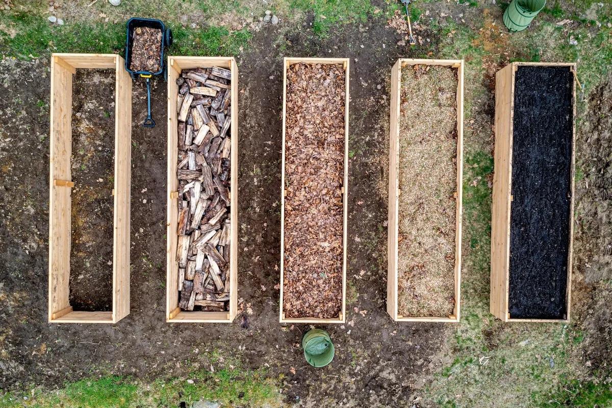 Nahaufnahme der verschiedenen Schichten zur Befüllung eines Hochbeets aus Holz.